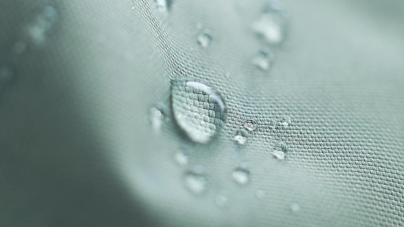 drop of water sitting on blue synthetic fabric.